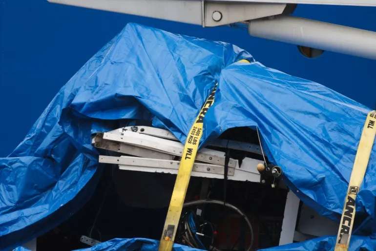 Pieces of the destroyed Titan submersible are covered by a tarp as they are unloaded to St John’s, Newfoundland, on Wednesday [David Hiscock/Reuters]