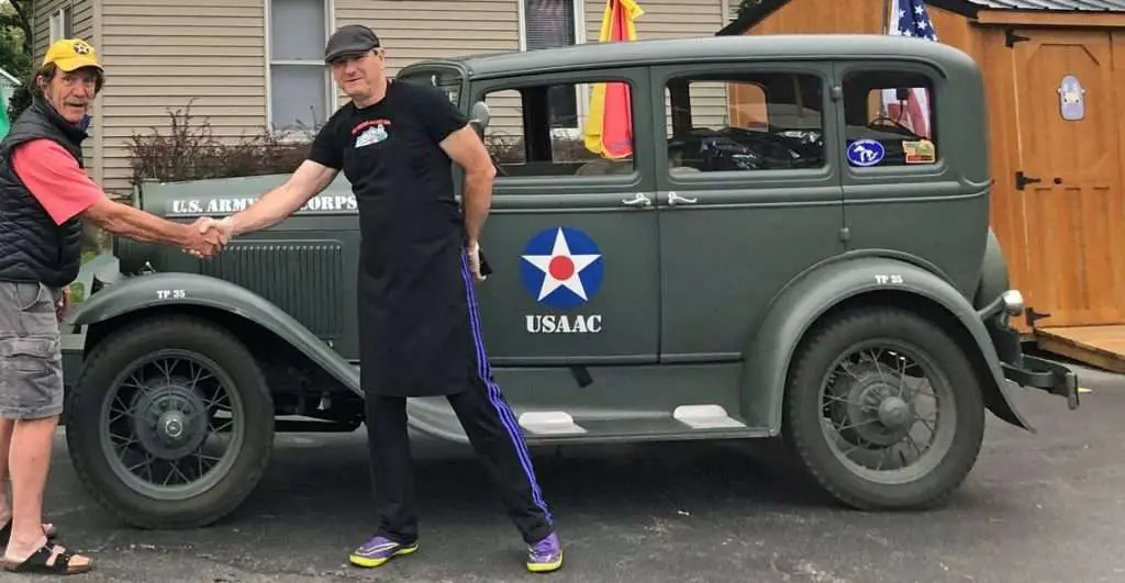 Jay Burbank, at left, and Tully Garrett of Wilmington, Illinois, pose in 2019 after Garrett signed his father’s name on Burbank’s 1931 Model A, in honor of the man’s military service, wartime injuries and experiences. It was the first of hundreds of veterans’ autographs Burbank has collected on the antique auto since then